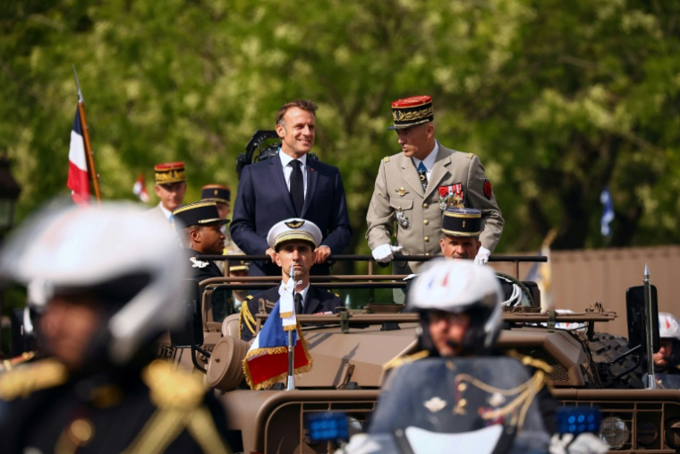 Le président français Emmanuel Macron (en haut à gauche) et le chef d'état-major des Armées, le général Thierry Burkhard (en haut à droite), passent en revue les troupes depuis le véhicule de commandement lors du défilé militaire annuel du 14 juillet sur l'avenue des Champs-Élysées à Paris, le 14 juillet 2025 ( POOL / Abdul Saboor )