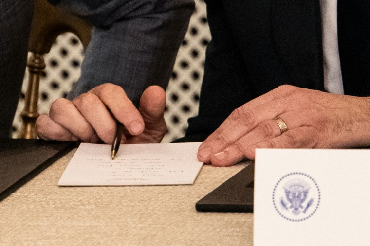 Le chef de cabinet adjoint de la Maison Blanche Stephen Miller lit la note manuscrite remise au président américain Donald Trump par le secrétaire d'Etat Marco Rubio signalant qu'un accord sur Gaza était proche, le 9 octobre 2025 à la Maison Blanche, à Washington ( AFP / Jim WATSON )