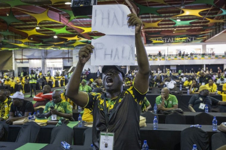 Lors d'une réunion du Congrès national africain (ANC) à Johannesburg, le 16 décembre 2022, un délégué brandit une pancarte où l'on peut lire "Phala Phala", en référence à un vol survenu dans la ferme du même nom appartenant au président sud-africain Cyril Ramaphosa ( AFP / GUILLEM SARTORIO )