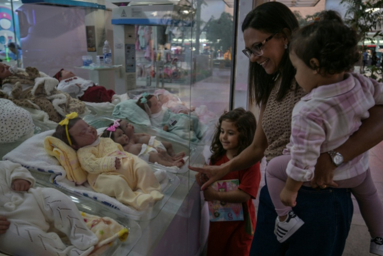 Une femme et ses enfants regardent des poupées "reborn" exposées au magasin Maternité Alana Babys à Campinas, dans l'État de Sao Paulo, au Brésil, le 16 mai 2025 ( AFP / Nelson ALMEIDA )