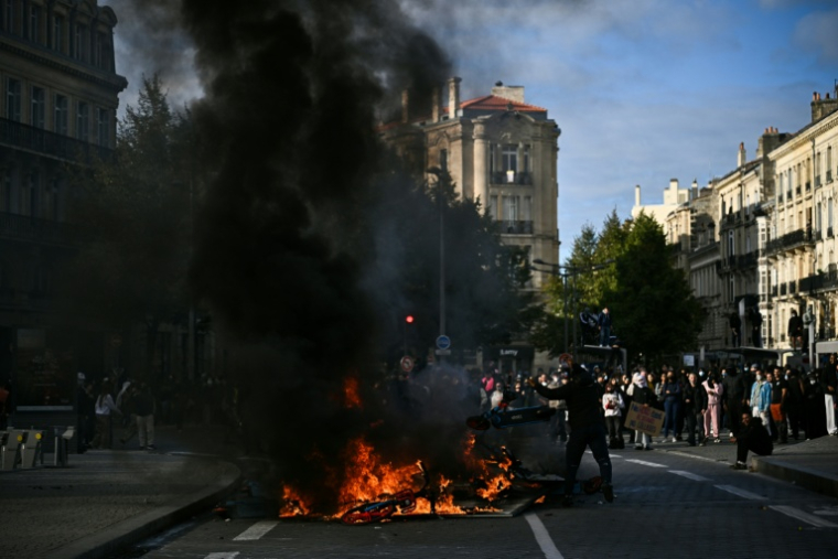 Un protestataire lance une trottinette électrique dans un feu lors d'une manifestation contre la vie chère à Bordeaux, le 17 octobre 2026 ( AFP / Christophe ARCHAMBAULT )
