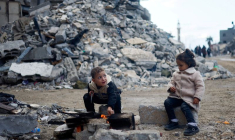 Des enfants palestiniens sont assis près du feu, à côté des décombres d'une maison, à Khan Younis