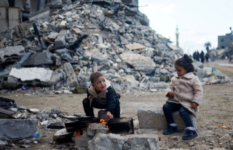 Des enfants palestiniens sont assis près du feu, à côté des décombres d'une maison, à Khan Younis