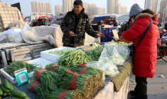 PHOTO DE FICHIER : Vendeur de légumes sur un marché à Pékin