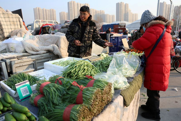 PHOTO DE FICHIER : Vendeur de légumes sur un marché à Pékin