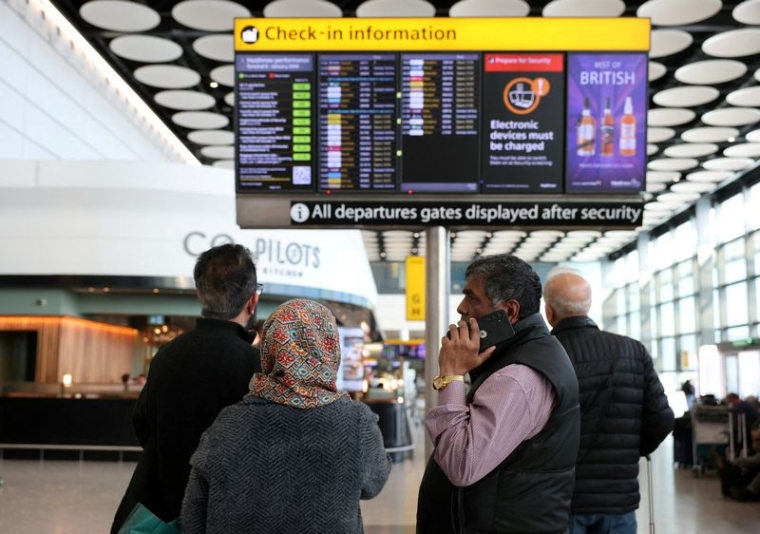Des voyageurs vérifient le tableau des départs affichant les vols annulés vers les pays du Moyen-Orient dans le contexte du conflit entre les États-Unis, Israël et l'Iran, à l'aéroport d'Heathrow
