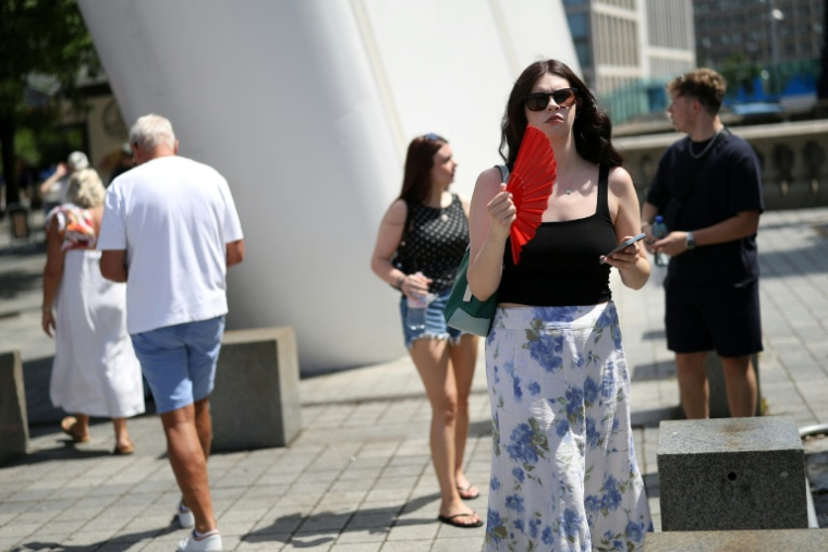 Une femme s'évente pour se rafraîchir dans une rue de Londres, le 23 juin 2026 lors d'un épisode de canicule en Europe ( AFP / Toby Shepheard )