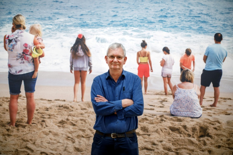 Martin Parr pose devant une de ses photos lors d'une exposition à Londres le 6 mars 2019 ( AFP / Tolga Akmen )