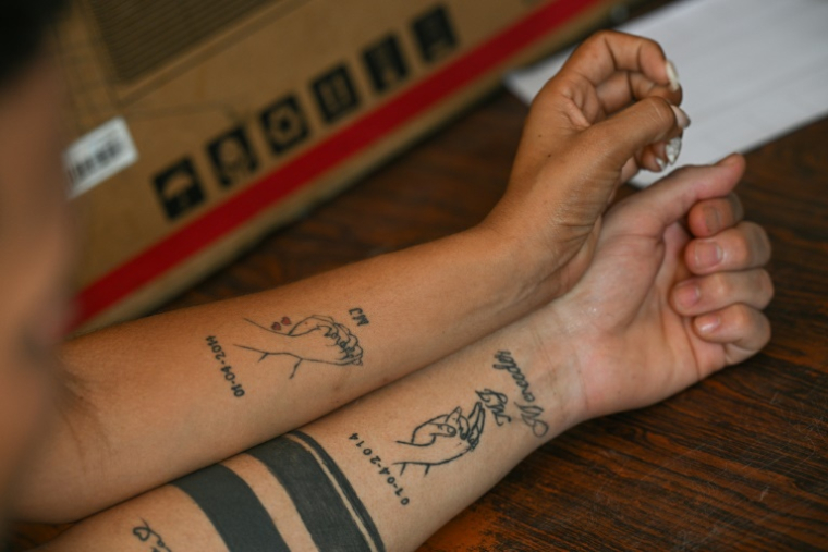 Mervin Yamarte, un migrant vénézuélien rapatrié d'une prison au Salvador, et sa femme montrent leurs tatouages lors d'une interview avec l'AFP dans le quartier de Los Pescadores à Maracaibo, au Venezuela, le 23 juillet 2025 ( AFP / Federico PARRA )