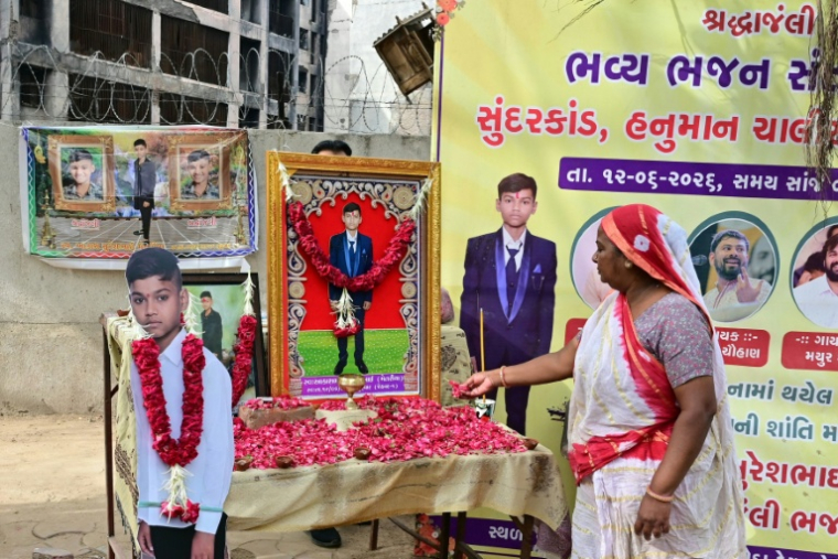Un proche d'Akash Patni, victime de l'accident du vol Air India 171, rend hommage devant des portraits de lui installés sur le lieu du crash, à l'occasion du premier anniversaire de la catastrophe, à Ahmedabad, le 12 juin 2026.  ( AFP / Shammi MEHRA )