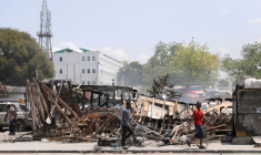 Des gens passent devant les restes de véhicules incendiés par des gangs, à Port-au-Prince