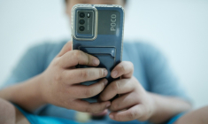 Un petit garçon regarde une vidéo sur son smartphone en attendant son père, à Jakarta, le 25 mars 2026 ( AFP / YASUYOSHI CHIBA )