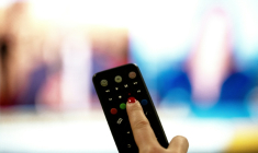 Une personne tient une télécommande pointée vers un écran de télévision, à Paris le 15 janvier 2025 ( AFP / Anna KURTH )