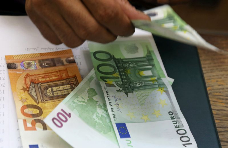 Un employé compte des billets en euros dans un bureau de change