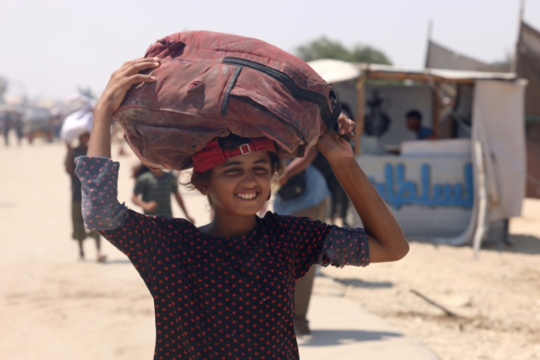 Une jeune palestinienne porte un sac d'aide humanitaire, qu'elle a récupéré après un largage, à Al-Mawassi dans le sud de la bande de Gaza, le 18 août 2025 ( AFP / - )