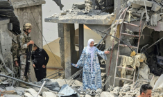 Une femme se fraye un chemin à travers les décombres sous le regard d'un soldat libanais, sur le site d'un immeuble résidentiel touché la veille par une frappe israélienne près de la ville de Burj al-Shamali, au sud de Tyr, le 27 mai 2026 ( AFP / KAWNAT HAJU )