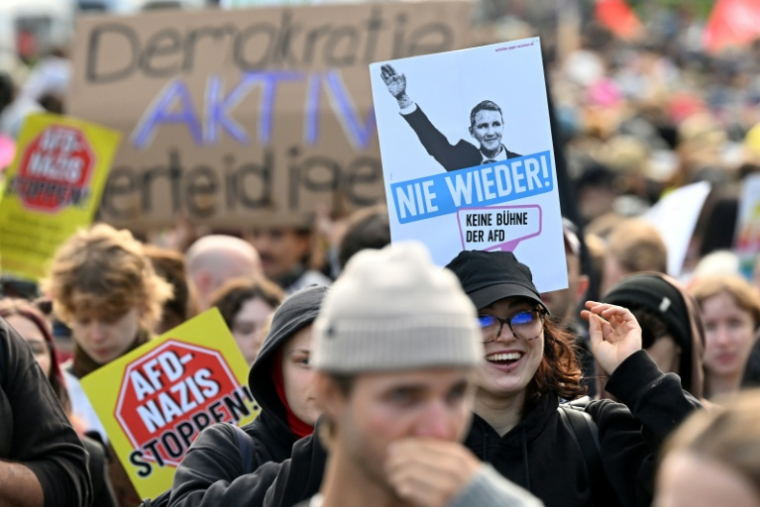 Des manifestants arborent une pancarte "Stoppez AfD-nazis" et une autre montrant un responsable régional de l'AfD semblant effectuer un salut nazi, avec la mention "Plus jamais ça - pas de tribune pour l'AfD" à Erfurt (Est de l'Allemagne) le 4 juillet 2026 ( AFP / RALF HIRSCHBERGER )