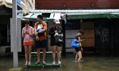 Des habitants sur un banc dans une rue de Bangkok, où l'état de catastrophe naturelle a été déclaré après des pluies diluviennes qui ont inondé habitations, commerces et axes de circulation, le 27 septembre 2026 ( AFP / Lillian SUWANRUMPHA )