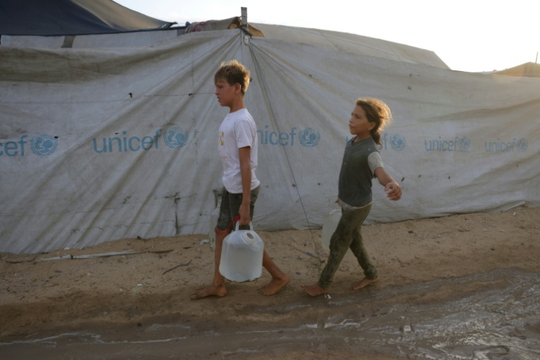 Nizar et sa soeur Hala, âgés respectivement de 14 et 11 ans, de retour d'un point de distribution d'eau à Al-Zawayda, dans le centre de la bande de Gaza, le 9 Octobre 2025. ( AFP / BASHAR TALEB )