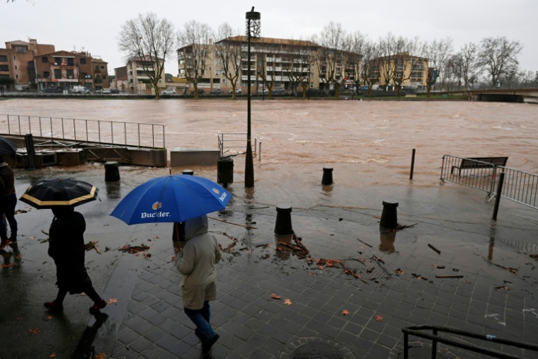 Des passants dans une rue inondée à Agde, après une crue de l'Hérault provoquée par des fortes pluies, le 23 décembre 2025 dans l'Hérault ( AFP / Sylvain THOMAS )