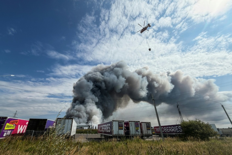 Un hélicoptère bombardier d'eau s'apprête à faire un largage au-dessus d'un incendie dans un centre logistique du géant russe de l'e-commerce Wildberries, le 16 août 2026 à Podolsk, près de Moscou ( AFP / TATYANA MAKEYEVA )