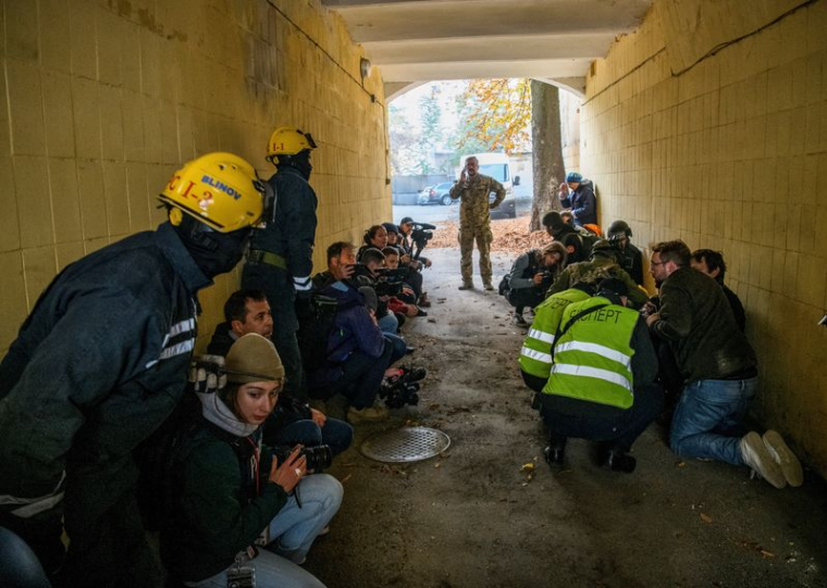 Des personnes secourues, des journalistes et des policiers se mettent à l'abri alors qu'une sirène d'alerte aérienne retentit lors d'une frappe de drone russe à Kiev, Ukraine