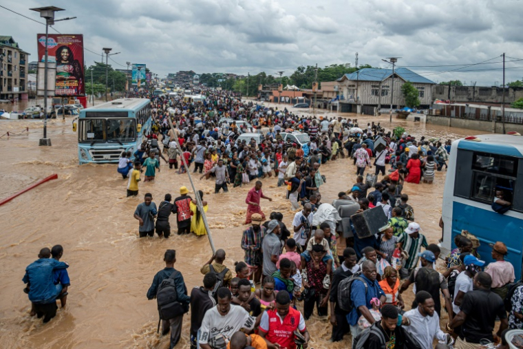 Des habitants dans un quartier inondé à Kinshasa, après des pluies diluviennes, le 6 avril 2025 en RDC ( AFP / Hardy BOPE )