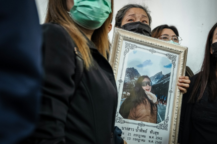 Une proche tient un portrait d'une des victimes de l'incendie dans un bar, le 14 juillet 2026 à l'hôpital général de la police de Bangkok  en Thaïlande ( AFP / chanakarn LAOSARAKHAM )