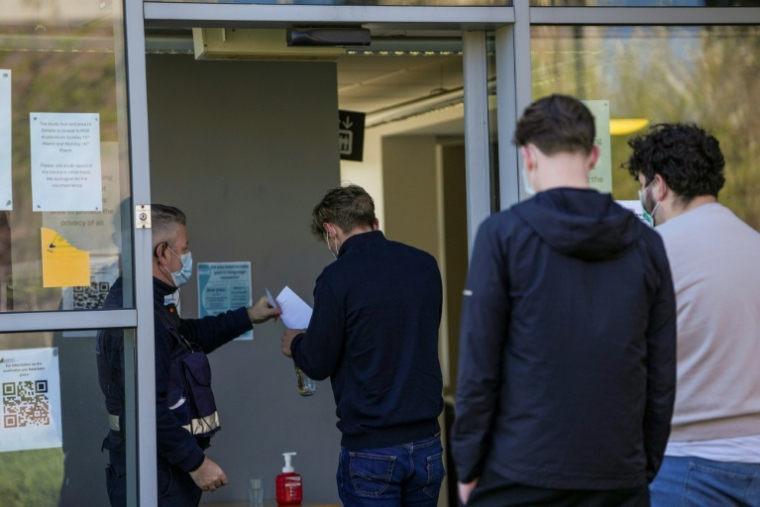 Des personnes portant des masques de protection font la queue pour récupérer des antibiotiques dans un bâtiment servant de centre médical sur le campus de l'Université du Kent à Canterbury, dans le sud-est de l'Angleterre, le 18 mars 2026, pendant une épidémie de méningite ( AFP / CARLOS JASSO )