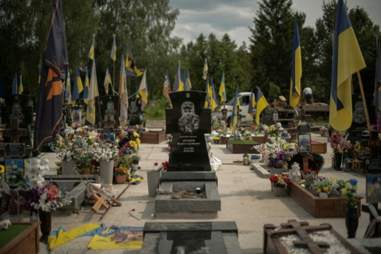 La tombe d'un soldat, entourée de drapeaux aux couleurs ukrainiennes, dans une des allées réservées aux soldats tués au combat contre les forces russes, dans le cimetière de Sumy, dans le nord-est de l'Ukraine, le 11 juin 2025 ( AFP / Florent VERGNES )