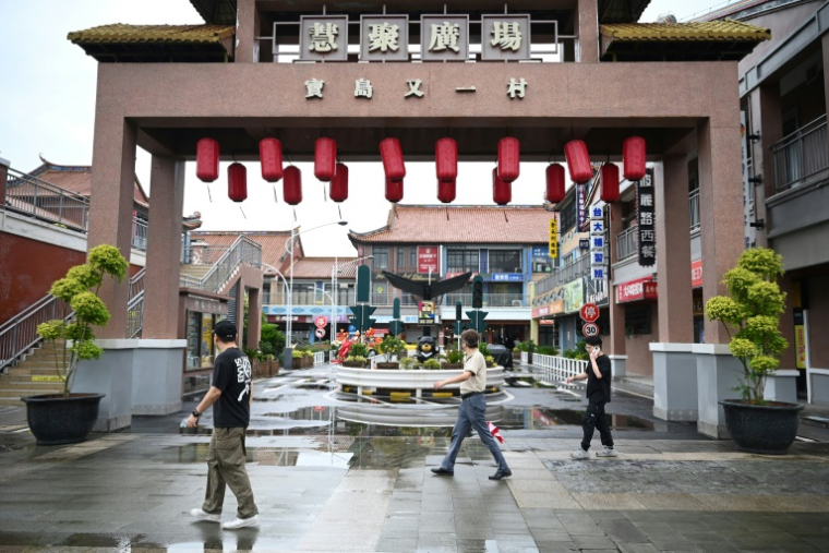 Des piétons passent devant la reconstitution d'un village de style taïwanais à Kunshan, dans la province orientale du Jiangsu, le 10 juin 2025 en Chine ( AFP / GREG BAKER )