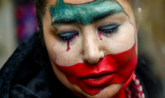 Une jeune femme iranienne, au visage peint aux couleurs du drapeau de son pays, participe au rassemblement interdit en Turquie de soutien à la contestation en Iran. Istanbul, 11 janvier 2025  ( AFP / Yasin AKGUL )