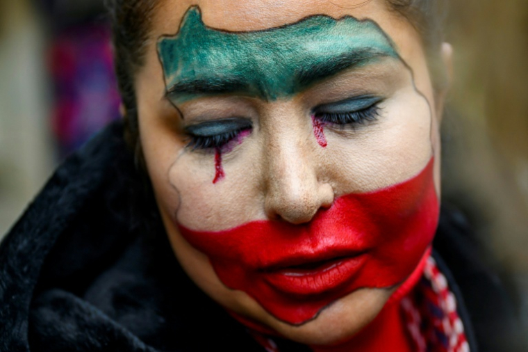 Une jeune femme iranienne, au visage peint aux couleurs du drapeau de son pays, participe au rassemblement interdit en Turquie de soutien à la contestation en Iran à Istanbul, le 11 janvier 2026  ( AFP / Yasin AKGUL )