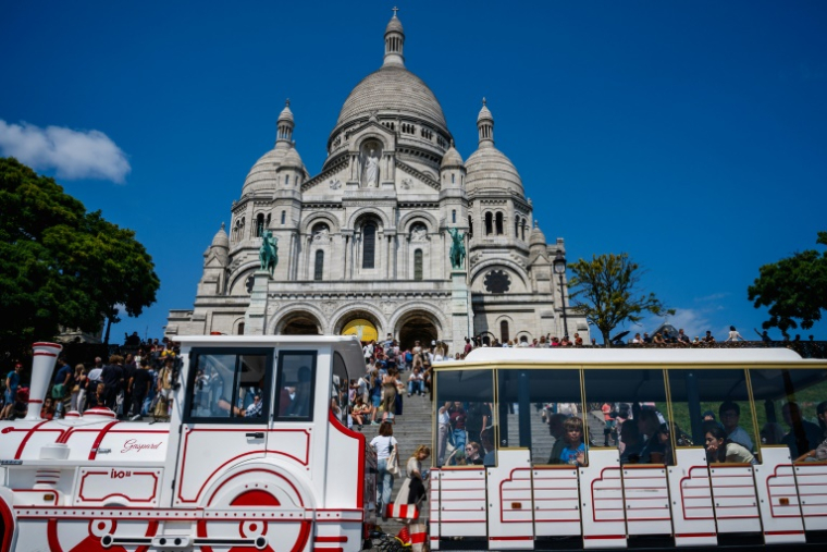 Un petit train passe devant la basilique du Sacré-Coeur, le 5 août 2025 à Paris ( AFP / Dimitar DILKOFF )