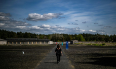 Une femme marche dans le camp de concentration de Ravensbrück, au nord de Berlin, le 25 avril 2025 ( AFP / John MACDOUGALL )