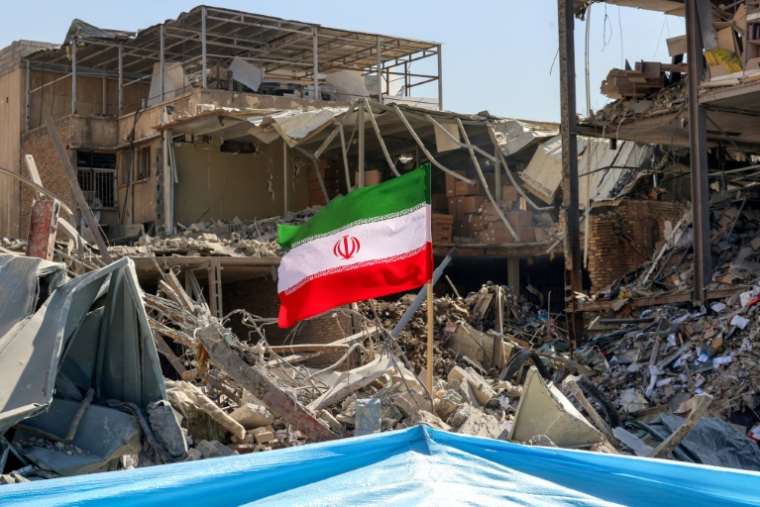 Un drapeau iranien planté dans les décombres d'un immeuble détruit, près de la place Ferdowsi à Téhéran, le 3 mars 2026 ( AFP / ATTA KENARE )