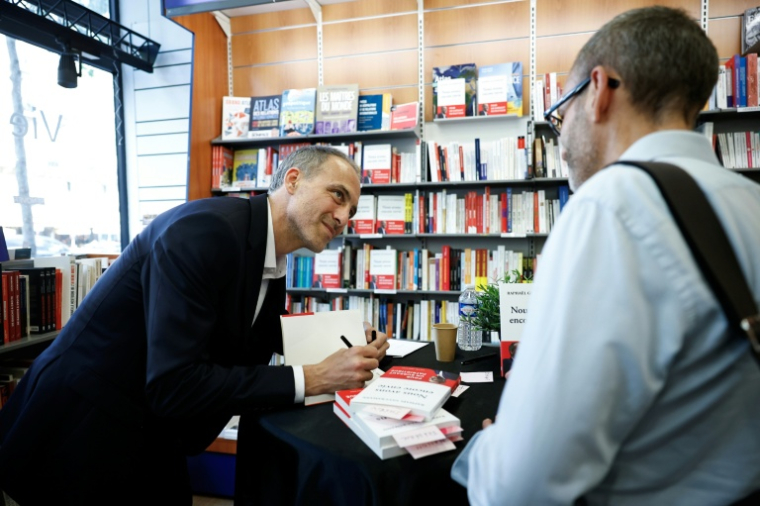 Raphaël Glucksmann signe un exemplaire de son livre "Nous avons encore envie", le 28 mai 2026 à Paris ( AFP / SIMON WOHLFAHRT )