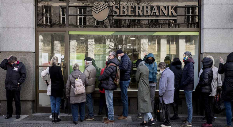 Des Russes font la queue devant les distributeurs pour tenter de convertir leurs roubles en devises étrangères. (© AFP)