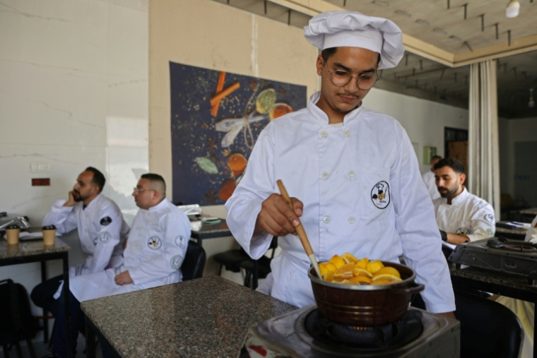 Des jeunes Palestiniens apprennent les bases de la cuisine à la Smile Kitchen Academy, dans le quartier de Rimal à Gaza, le 24 juin 2026 ( AFP / Omar AL-QATTAA )