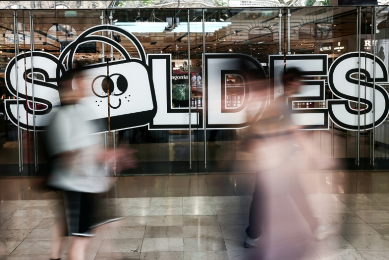 Des passants marchent à proximité de l'entrée d'un centre commercial annonçant les soldes, le 25 juin 2025 à Paris ( AFP / Thibaud MORITZ )