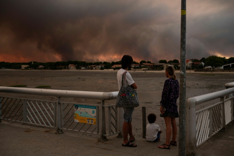 Des gens regardent les fumées d'un incendie à Lège-Cap-Ferret depuis la plage d'Andernos-les-Bains, en Gironde, le 23 juillet 2026 ( AFP / Olivier MORIN )