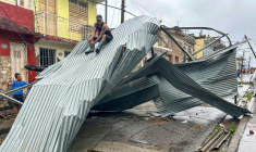 Un homme assis sur une partie du toit de sa maison, à Santiago de Cuba, le 29 octobre 2025 ( AFP / YAMIL LAGE )