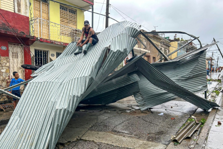Un homme assis sur une partie du toit de sa maison, à Santiago de Cuba, le 29 octobre 2025 ( AFP / YAMIL LAGE )