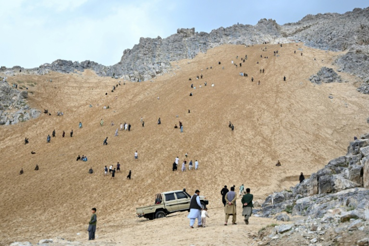 Des Afghans sur la pente sableuse de la montagne Reg-e-Rawan dans la région de Sayad, le 24 avril 2026, en Afghanistan ( AFP / Wakil KOHSAR )
