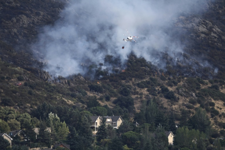 Photo prise le 25 juillet 2026 montrant un hélicoptère versant de l'eau sur un feu qui menace de s'approcher du village de Robledo de Chavela, à 60 km à l'ouest de Madrid ( AFP / Oscar DEL POZO )