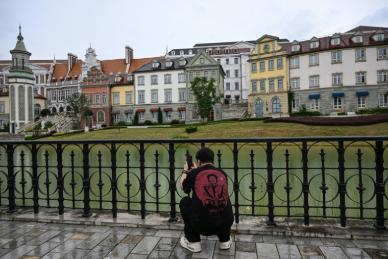 Un homme photographie le centre de données au style européen de l'entreprise technologique chinoise Huawei, situé dans la nouvelle zone de Guian, à Guiyang,d ans la province du Guizhou, le 24 juillet 2026 dans le sud-ouest de la Chine ( AFP / Jade GAO )