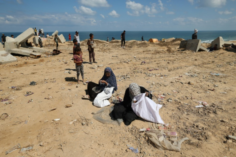 Des Palestiniennes fouillent le sol à la recherche de restes de colis de vivres à Nousseirat, dans le centre de la bande de Gaza, le 5 août 2025 ( AFP / Eyad BABA )