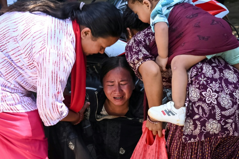 Une femme s'effondre tandis qu’elle attend l’arrivée de ses proches dans un camp militaire après avoir été secourue des zones touchées par des crues subites, dans la ville de Battar Bazar, dans le district de Nuwakot au Népal, le 27 août 2026 ( AFP / Prakash MATHEMA )