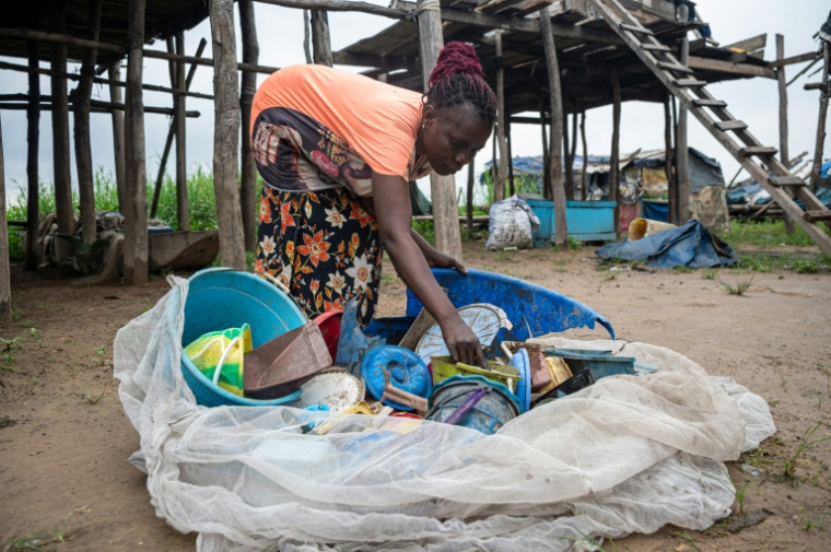 Une femme trie des objets en plastique ramassés dans le fleuve Congo sur l'île de Kimpoko, à Kinshasa, le 27 avril 2026 en RDC ( AFP / Hardy BOPE )