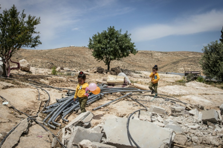 Deux fillettes palestiniennes marchent dans les décombres du hameau de Khallet Al-Dabaa, en Cisjordanie occupée, le 6 mai 2025, après la destruction par les forces israéliennes des maisons de ce village ( AFP / JOHN WESSELS )